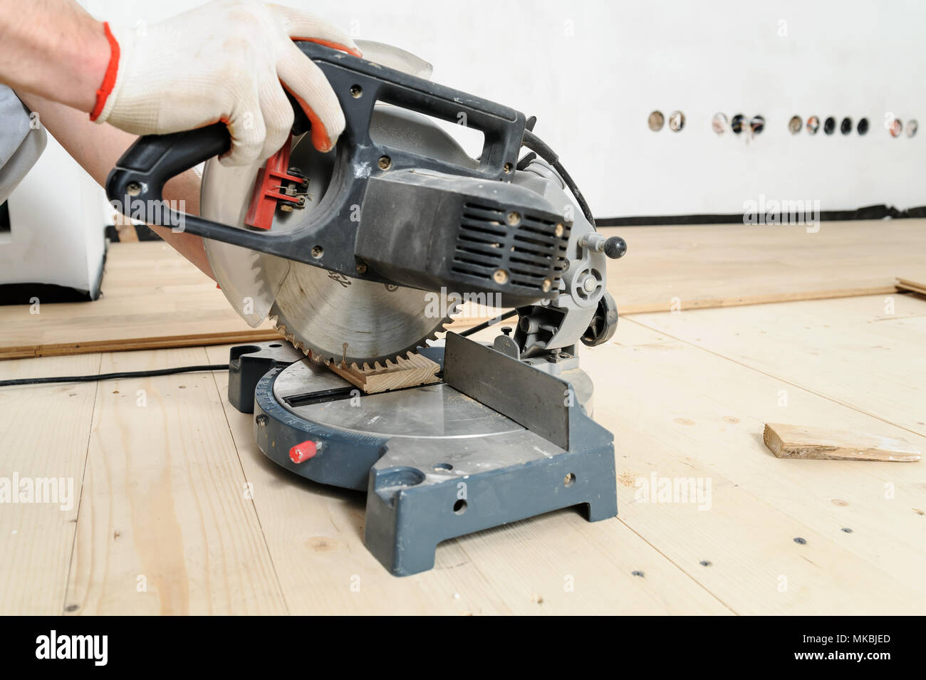 Worker cuts wooden floorboards using a circular saw Stock Photo