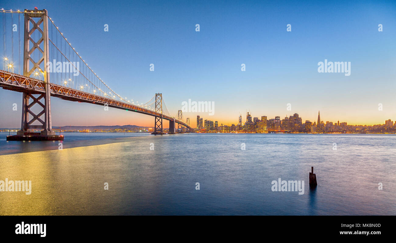 Classic panoramic view of San Francisco skyline with famous Oakland Bay Bridge illuminated in beautiful golden evening light at sunset in summer Stock Photo