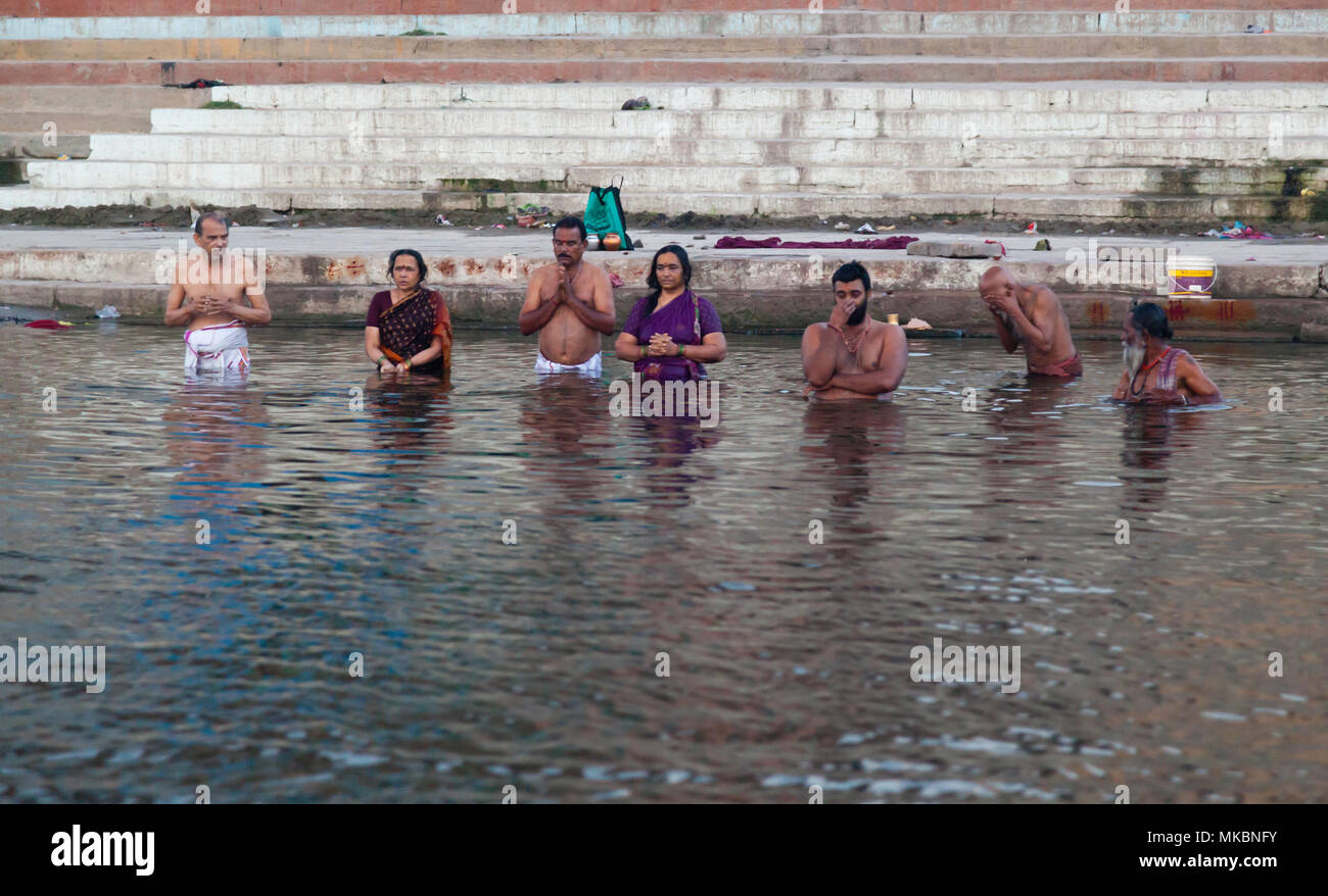 Family and friends take an early morning dip in the Ganges at Varanasi to pray and wash away their sins. Stock Photo