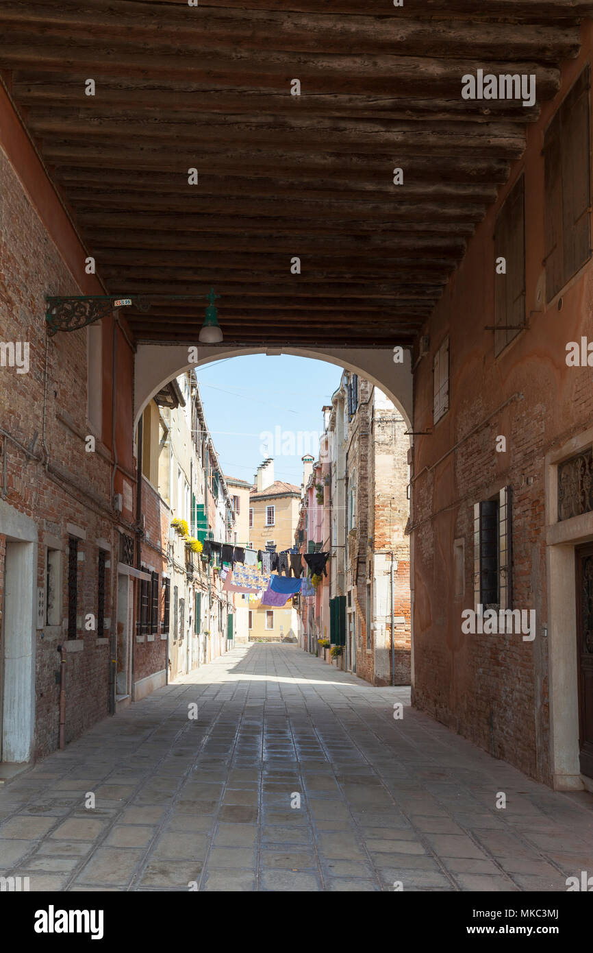 View through a sotoportego (covered walkway) of washing hanging on lines on washday , Castello, Venice, Italy Stock Photo