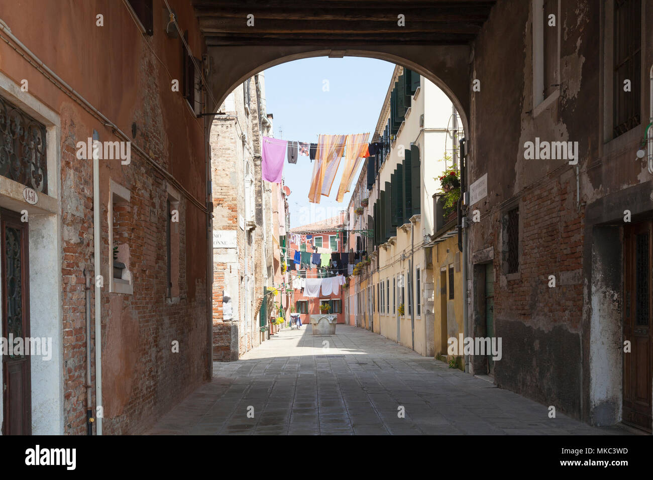 View through an arched  sotoportego (covered walkway) of washing hanging on lines on washday , Castello, Venice, Italy Stock Photo