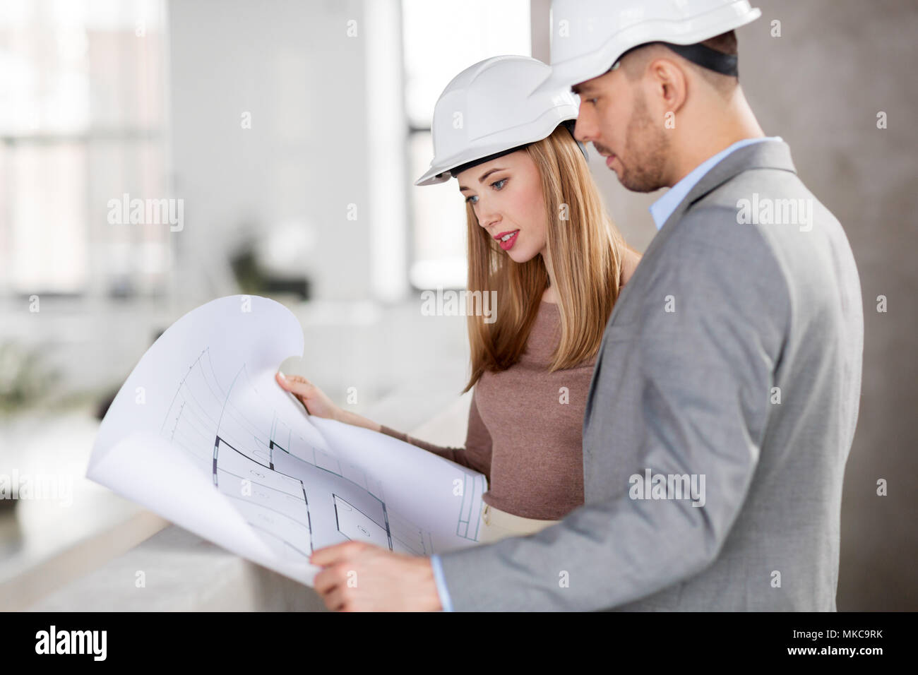 architects with blueprint and helmets at office Stock Photo