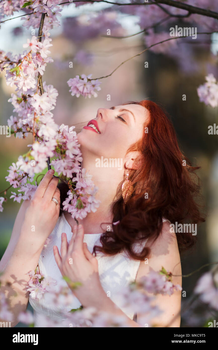 portrait of a beautiful redheaded woman at a flowering tree Stock Photo ...