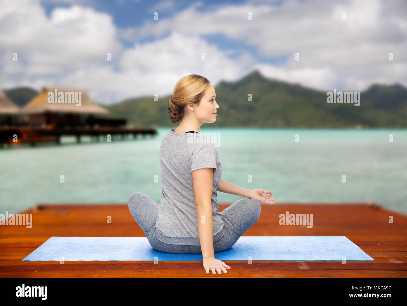 woman making yoga in twist pose on mat outdoors Stock Photo - Alamy