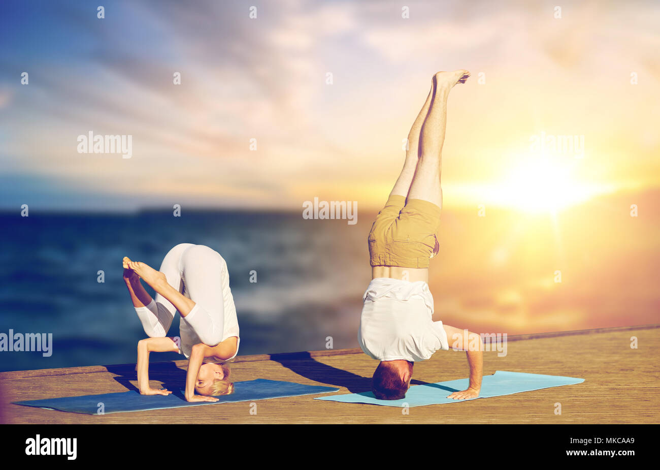 couple doing yoga headstand outdoors Stock Photo