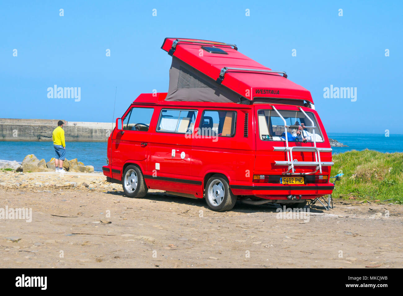 A 1988  bright red Volkswagen Westfalia motor caravan with the roof up, parked at the seaside in North Yorkshire Stock Photo