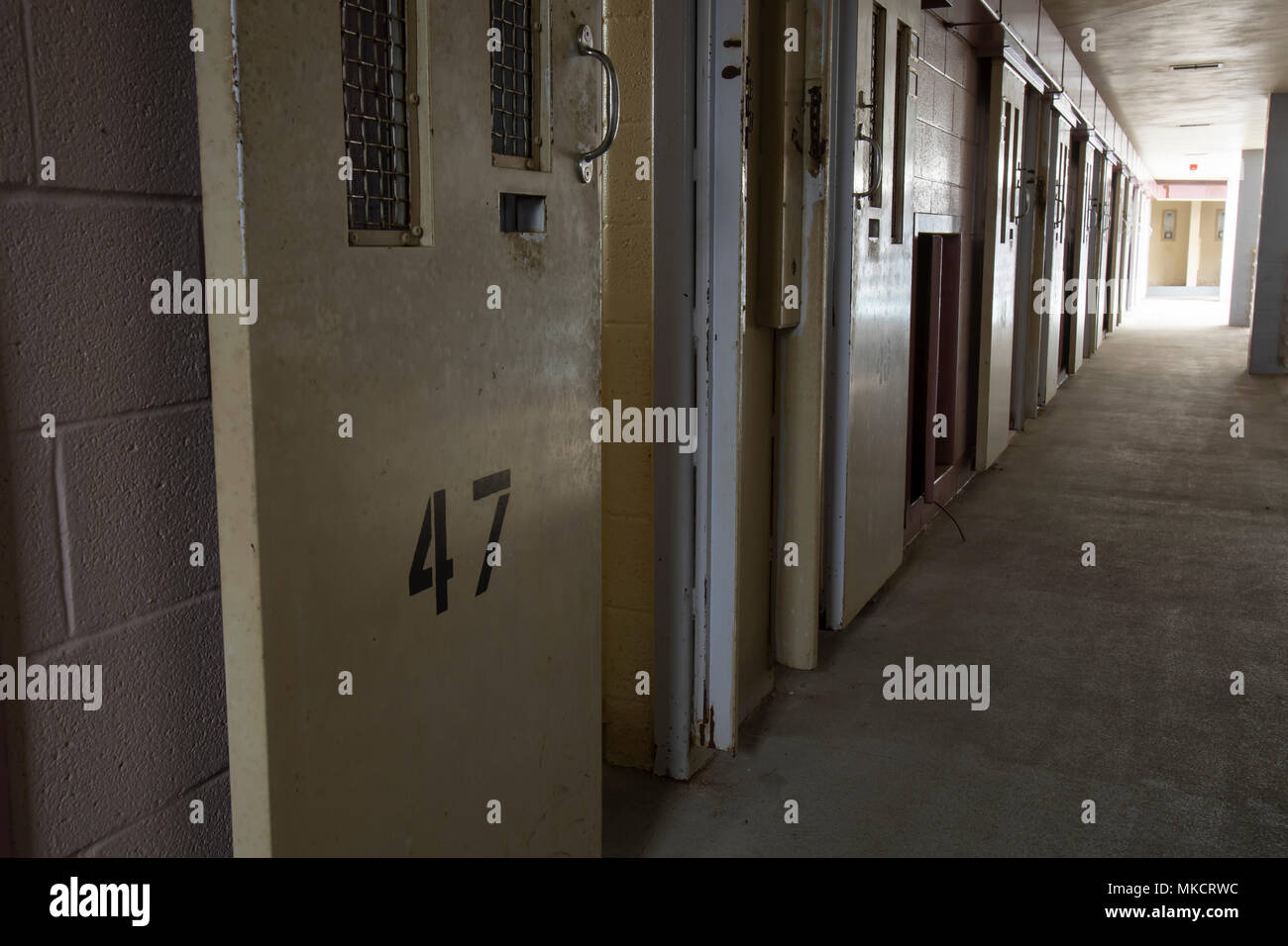Row Of Open Cell Doors In Hallway Of Abandoned Prison With