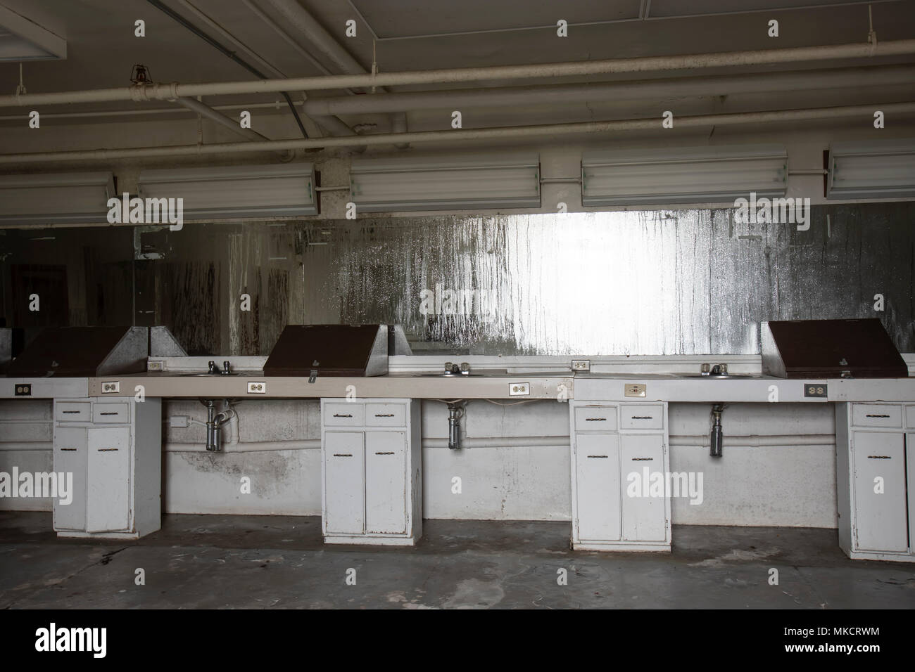 Interior of old, abandoned beauty salon with sinks and work stations with condensation on mirrors and dirt on floors. Stock Photo