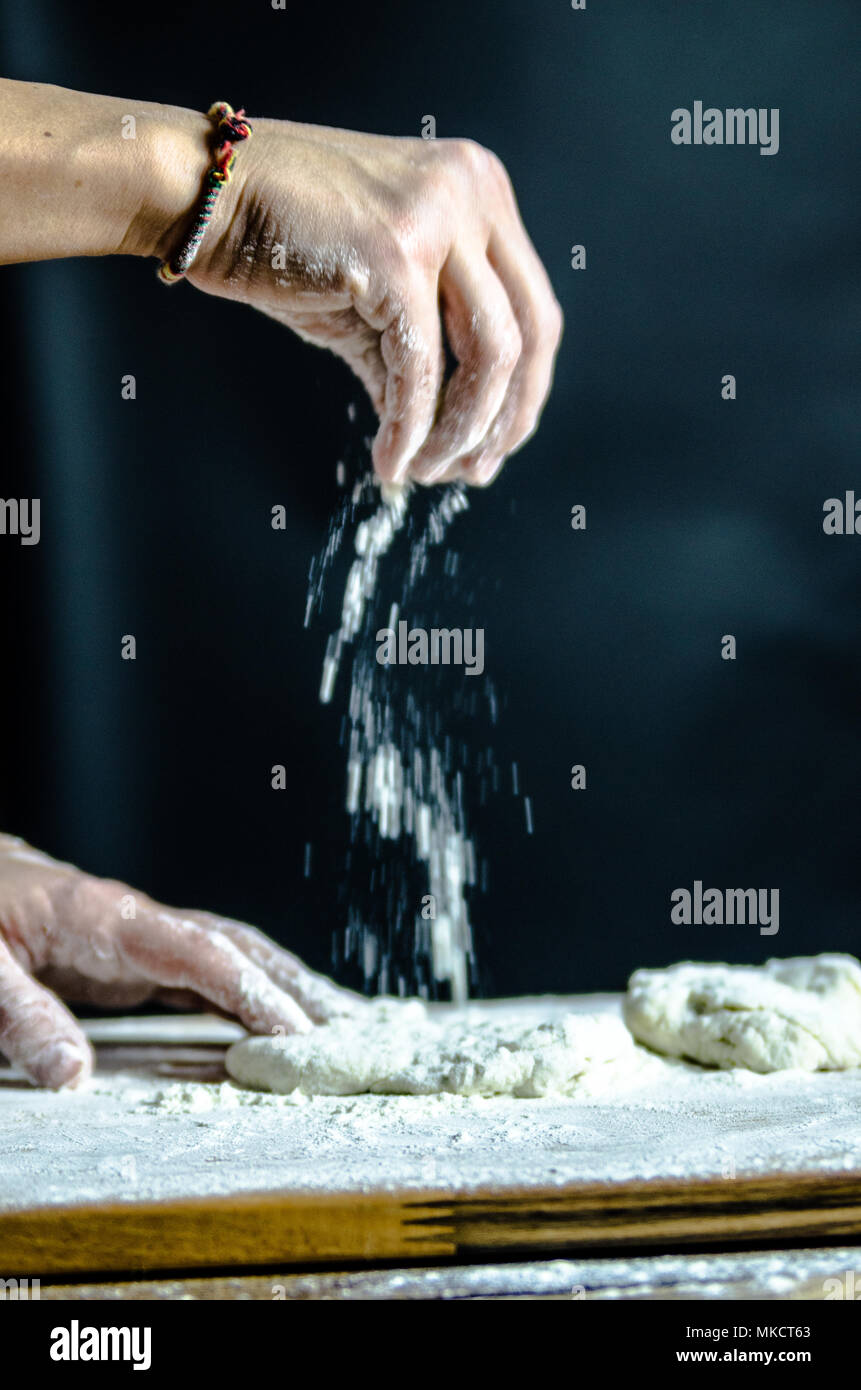 dough docked on the wooden board, traditional pretzel preparation, baker making bread dough in the bakery. hands played with flour and dough. Stock Photo
