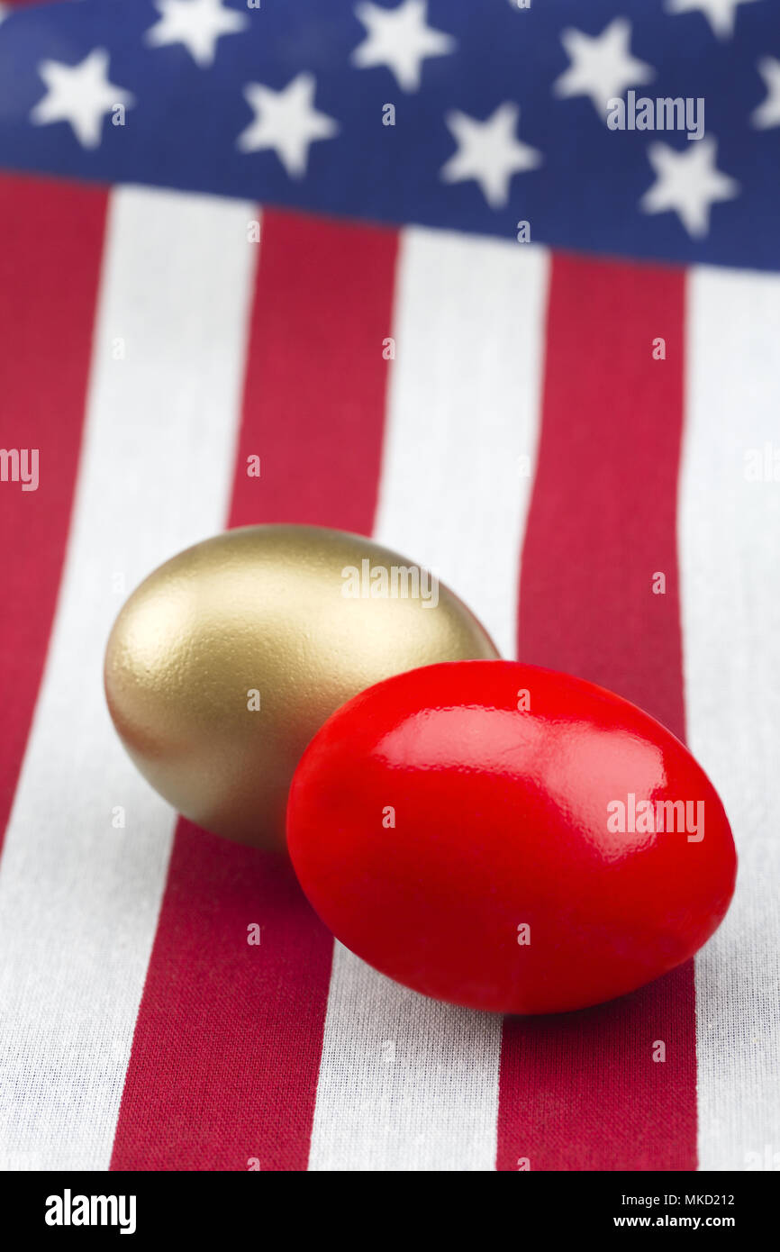 red and gold nest eggs placed on American flag in vertical photograph.  Selective focus on opposing symbols of profit and loss, success and failure, r Stock Photo