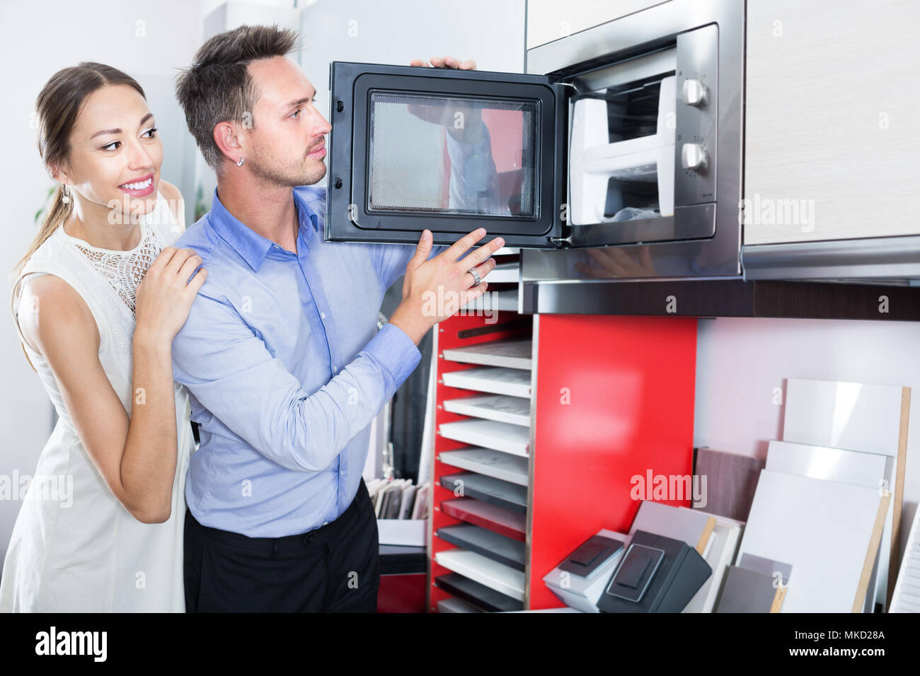 Smiling family couple choosing new microwave in furniture showroom Stock Photo