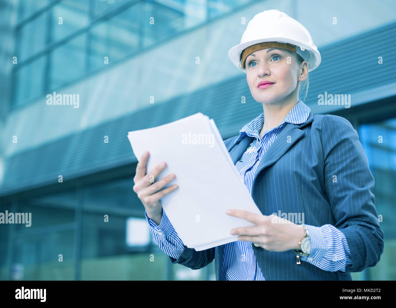 Employee woman in suit standing in helmet with paper documents Stock ...
