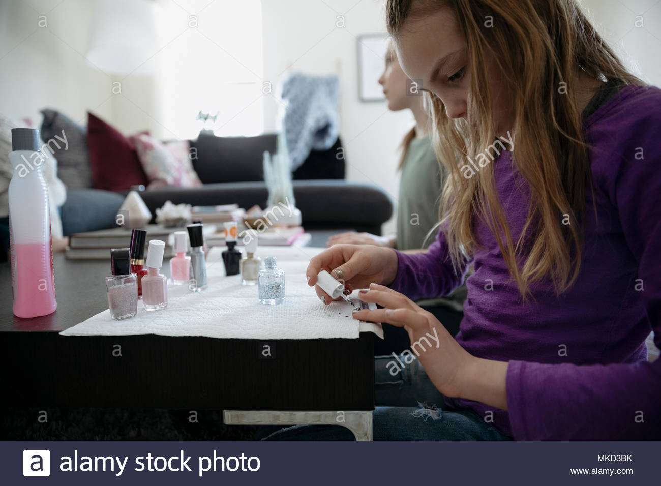 Focused girl painting fingernails with fingernail polish in living room Stock Photo