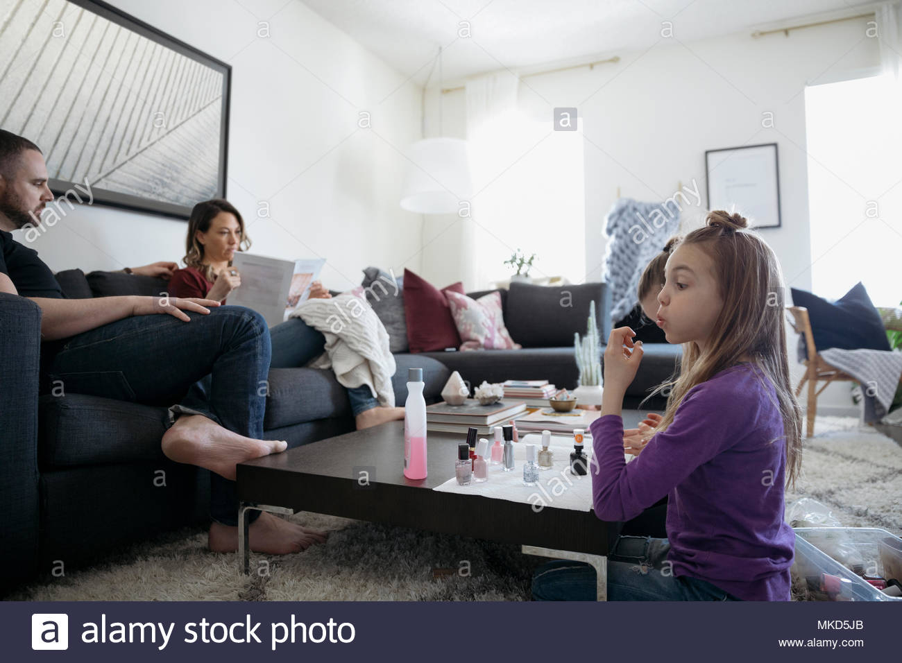 Girl painting fingernails with fingernail polish in living room Stock Photo