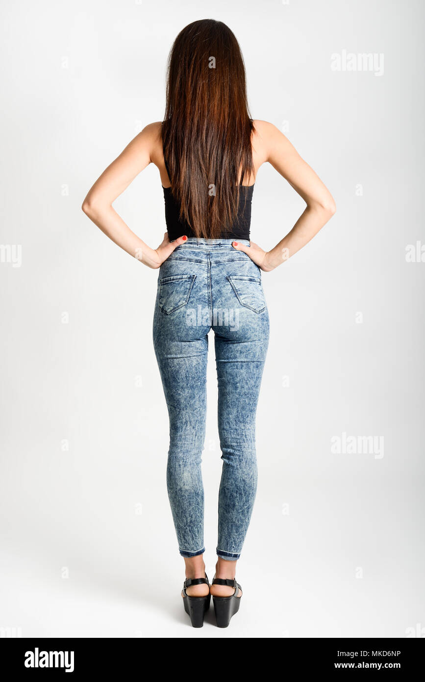 Back side of woman wearing high-waisted jeans. Studio shot. Girl with