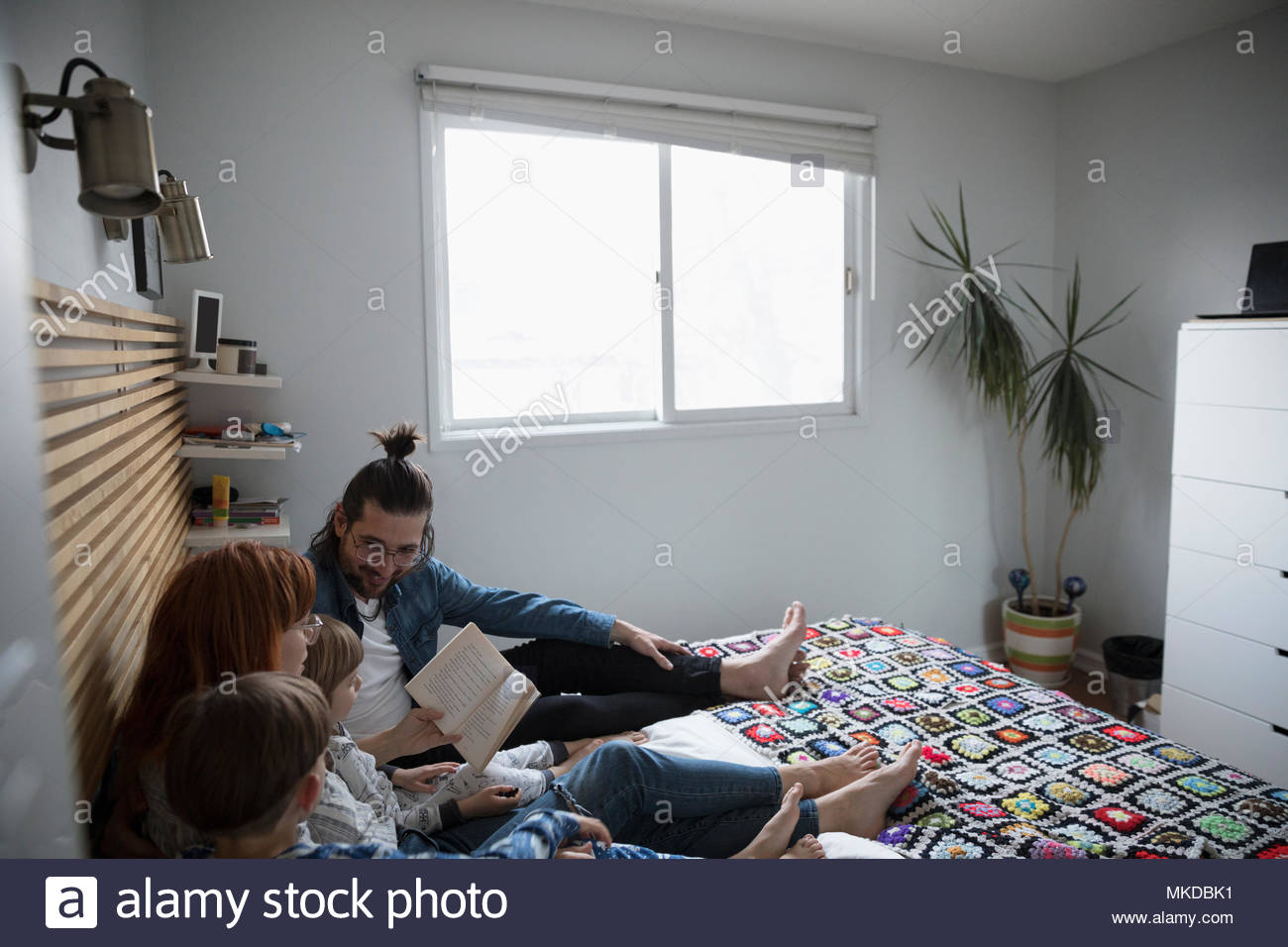 Family reading bedtime story book on bed Stock Photo