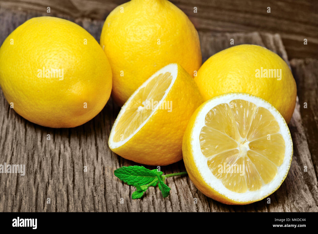 Heap of fresh lemons with mint on old wooden table Stock Photo