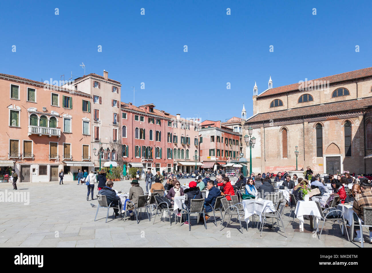 Tourists eating at a restaurant in Campo Santo Stefano, San Marco, Venice, Italy enjoying the spring sunshine Stock Photo