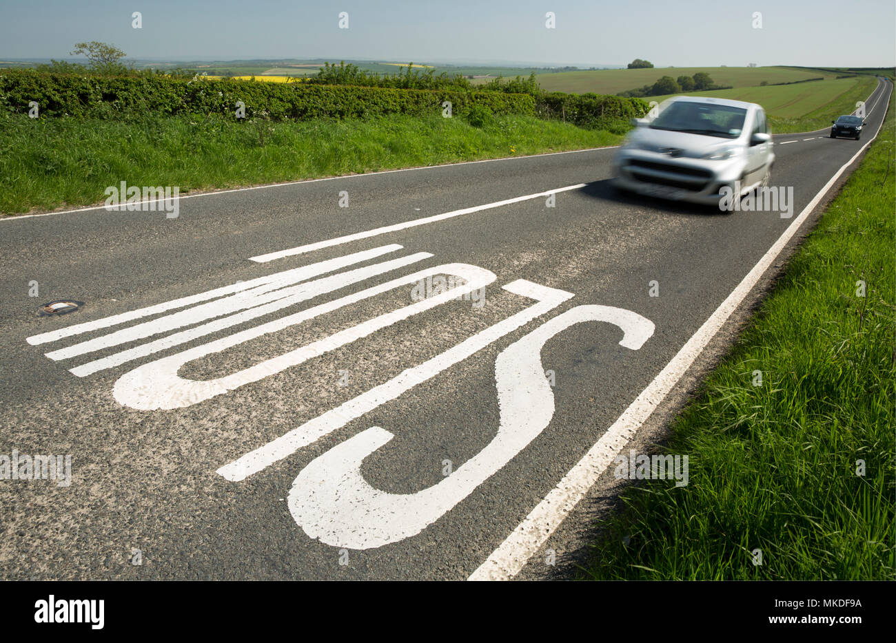 A SLOW sign on the brow of a hill on a road through the Dorset countryside leading into the distance to Dorchester In Dorset England UK. May 7 2018 Stock Photo