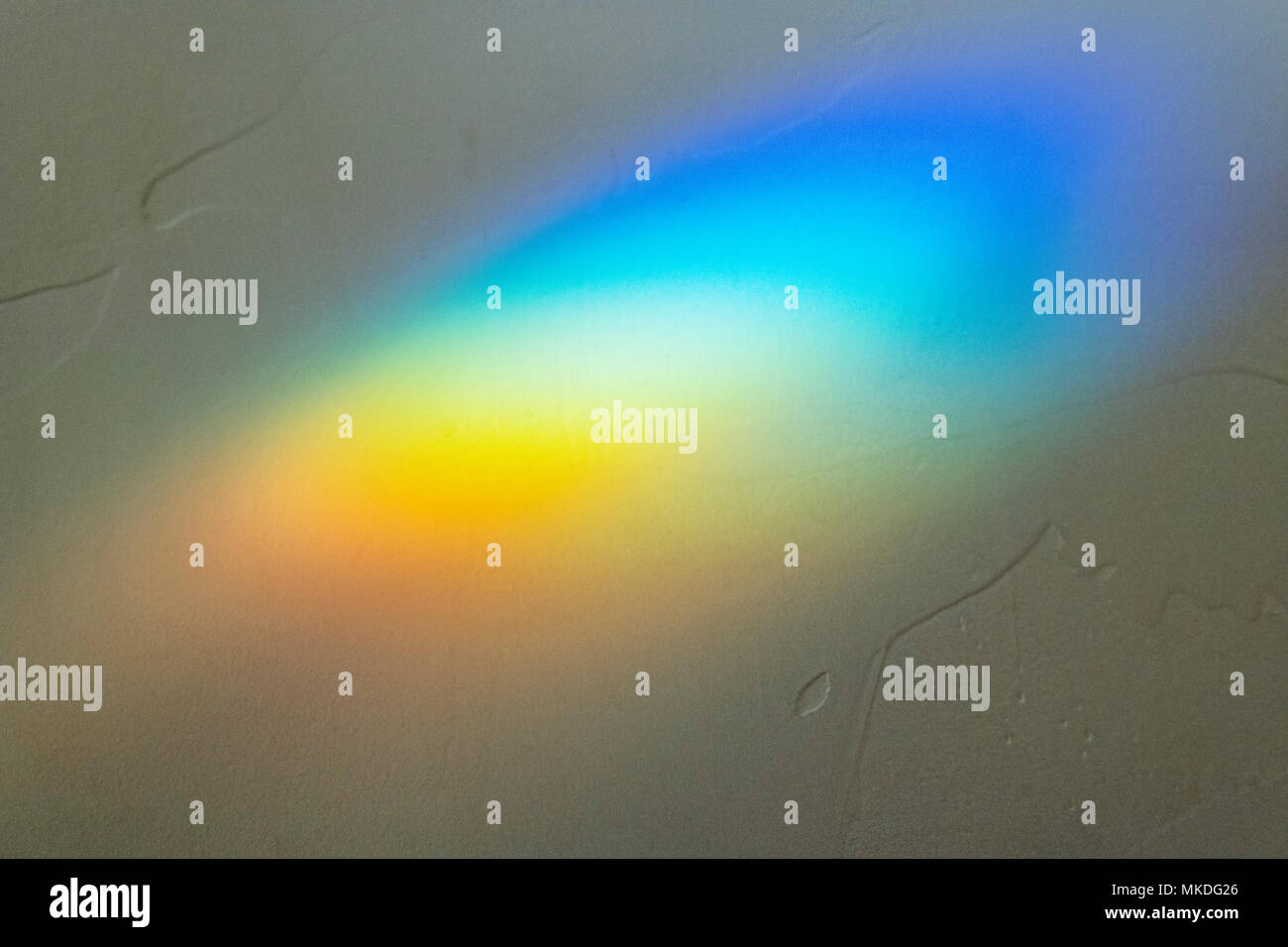Sunlight through stained glass creates abstract prism effect on wall Stock Photo