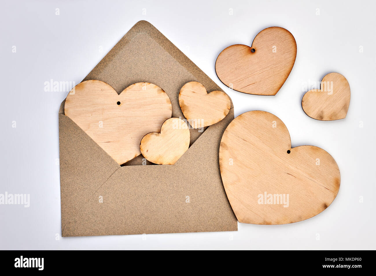 Opened envelope and plywood hearts. Vintage style envelope and wooden hearts on white background. Happy Valentines Day. Stock Photo