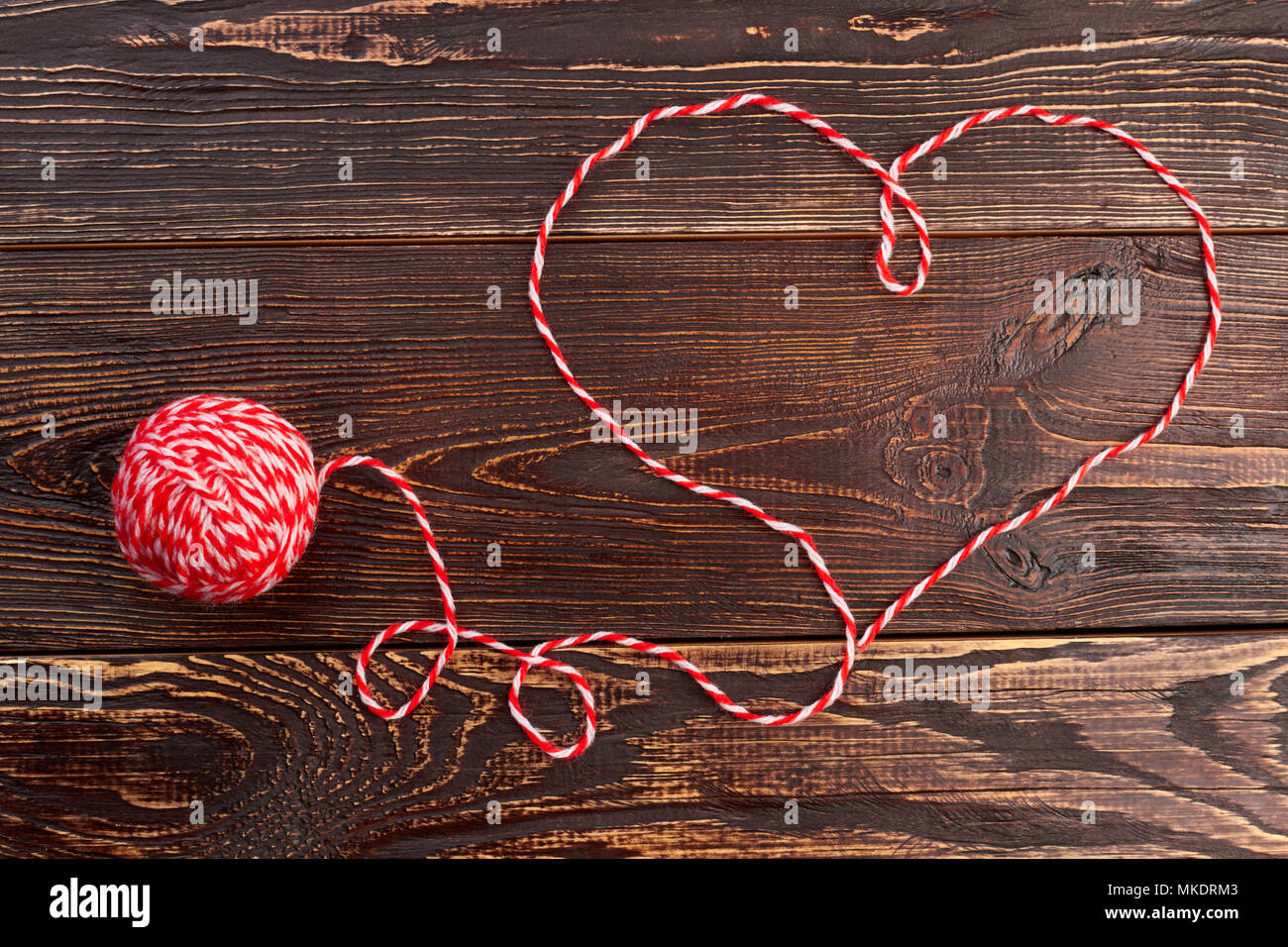 Shape of heart from woolen thread. Woolen ball on brown wooden ...