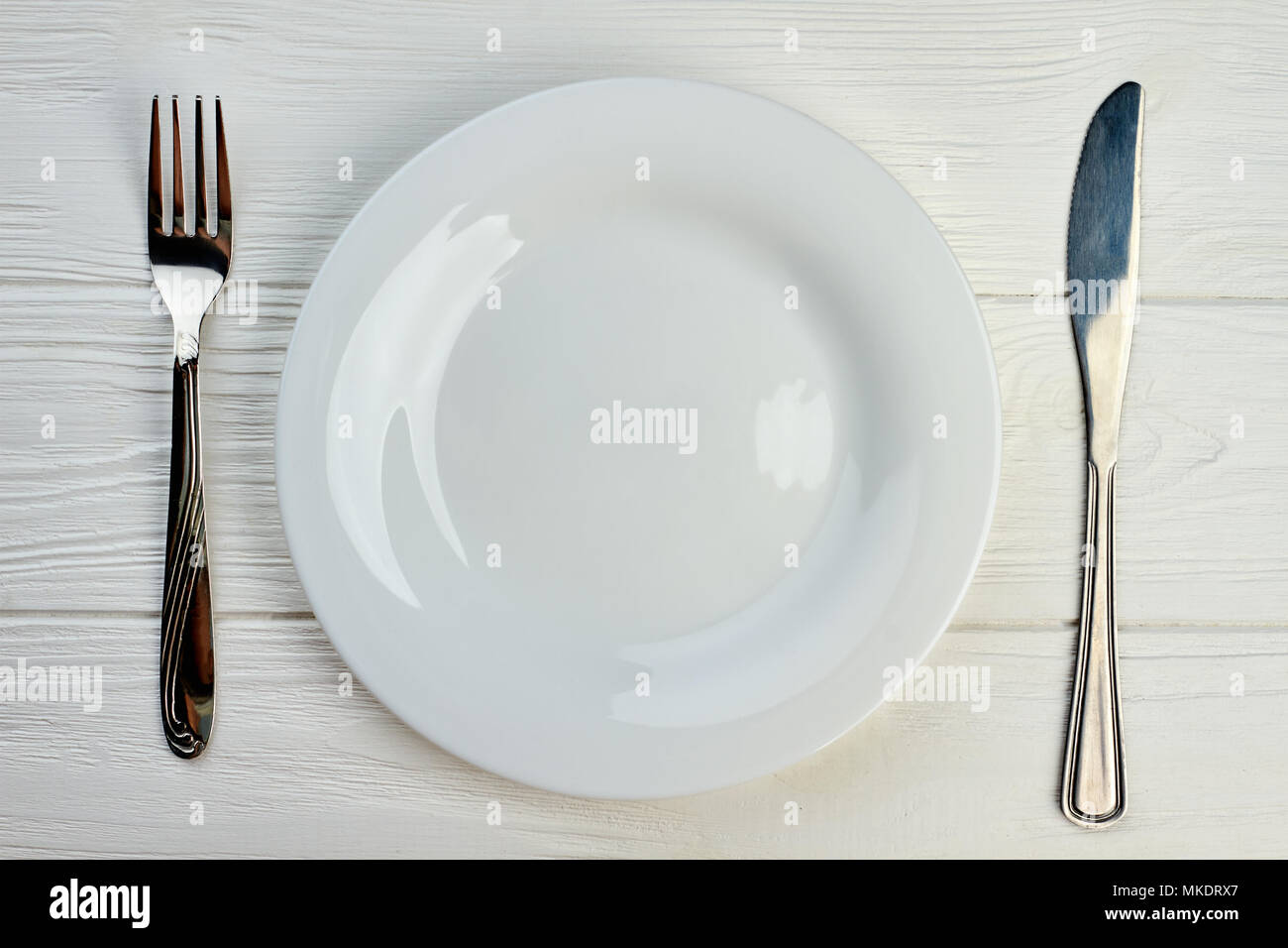 Empty plate, fork and knife. Kitchen utensil on white wooden table ... Empty plate, fork and knife. Kitchen utensil on white wooden table ...