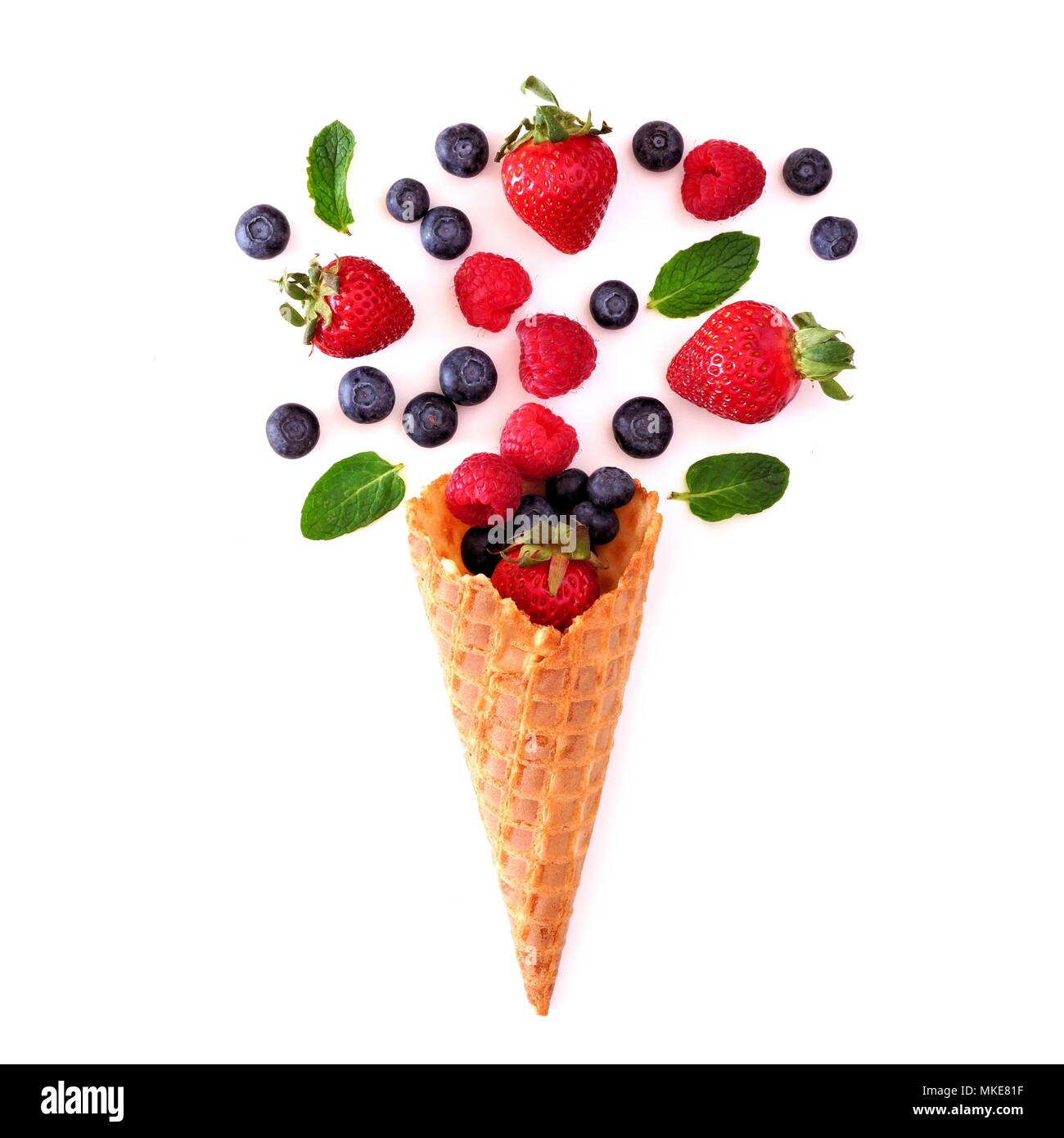 Assorted berry fruit in waffle ice cream cone. Flat lay concept over a white background. Stock Photo
