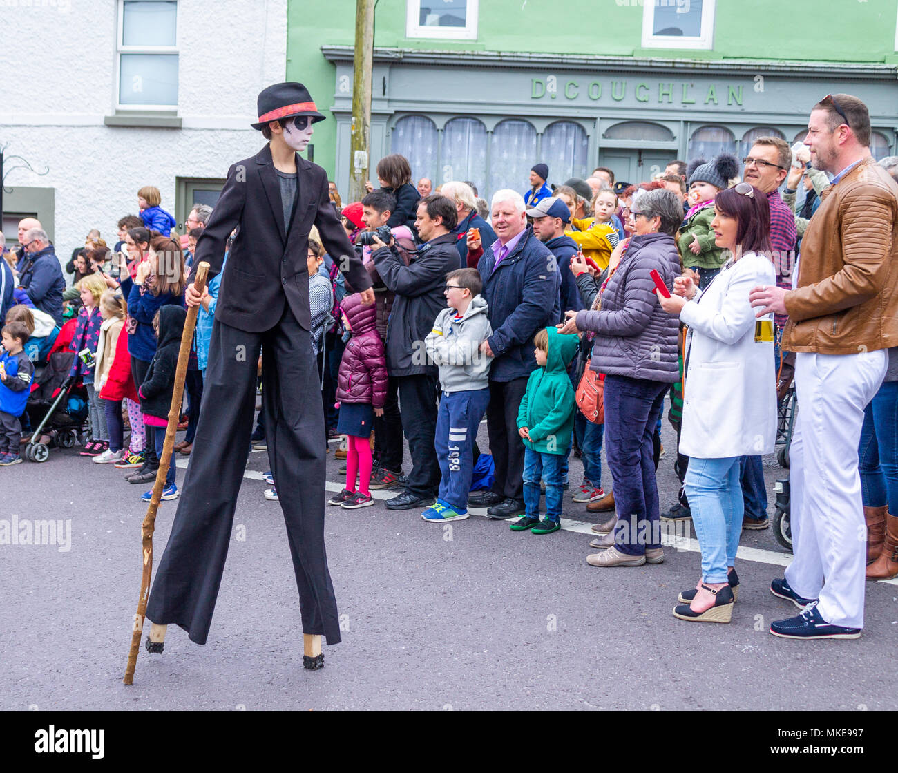 street performers taking part in a jazz festival street procession, showing their bright costumes and dancing with the music.Ballydehob, ireland. Stock Photo