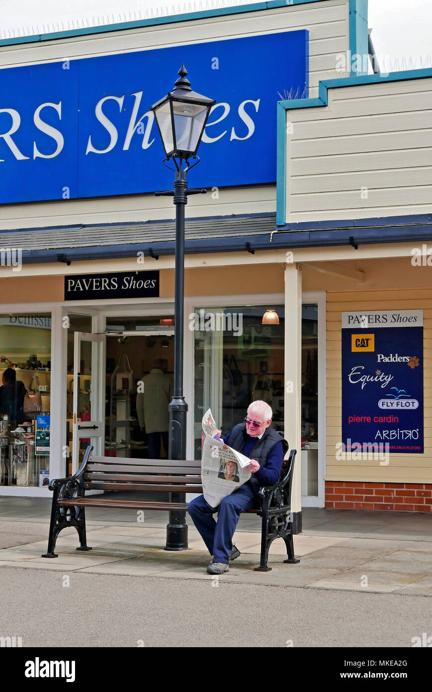 Man sat on bench reading newspaper at Affinity Outlets(formerly Freeport),Fleetwood Stock Photo