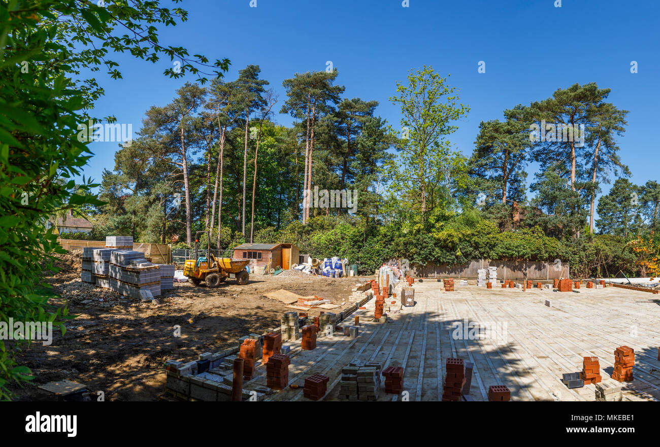 View of a suburban residential building site for a new house on a brownfield site with construction materials and dumper truck on a sunny day Stock Photo