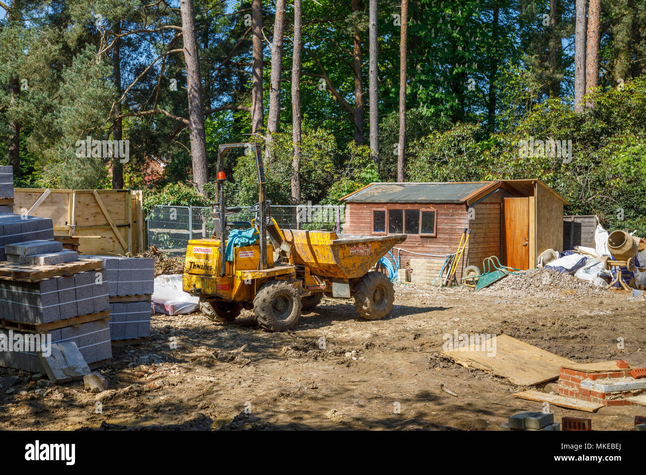 View of a suburban residential building site for a new house on a brownfield site with construction materials and dumper truck on a sunny day Stock Photo