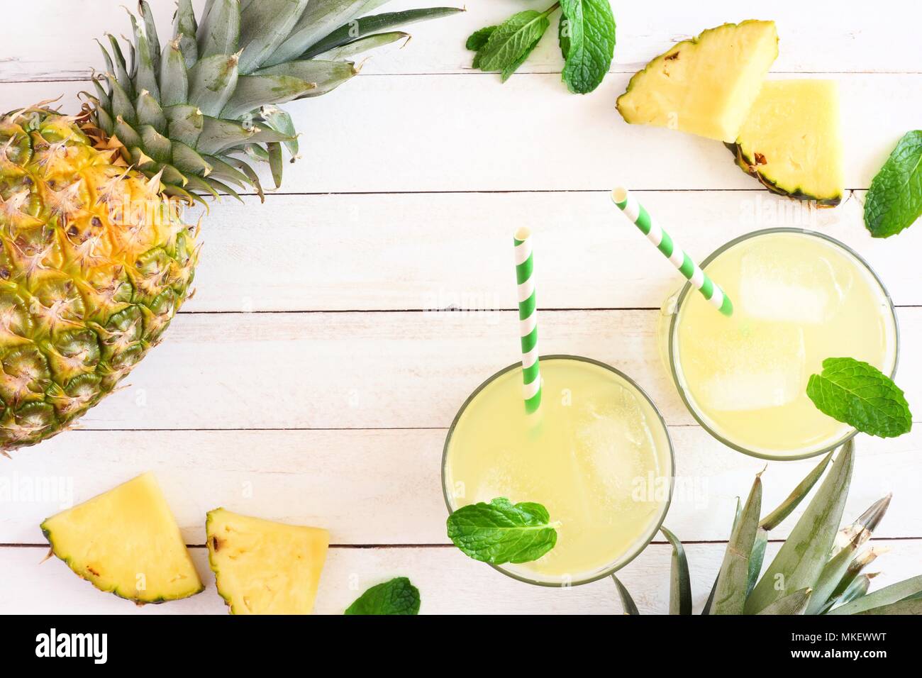 Two glasses of pineapple juice with fruit. Top view frame on a white ...