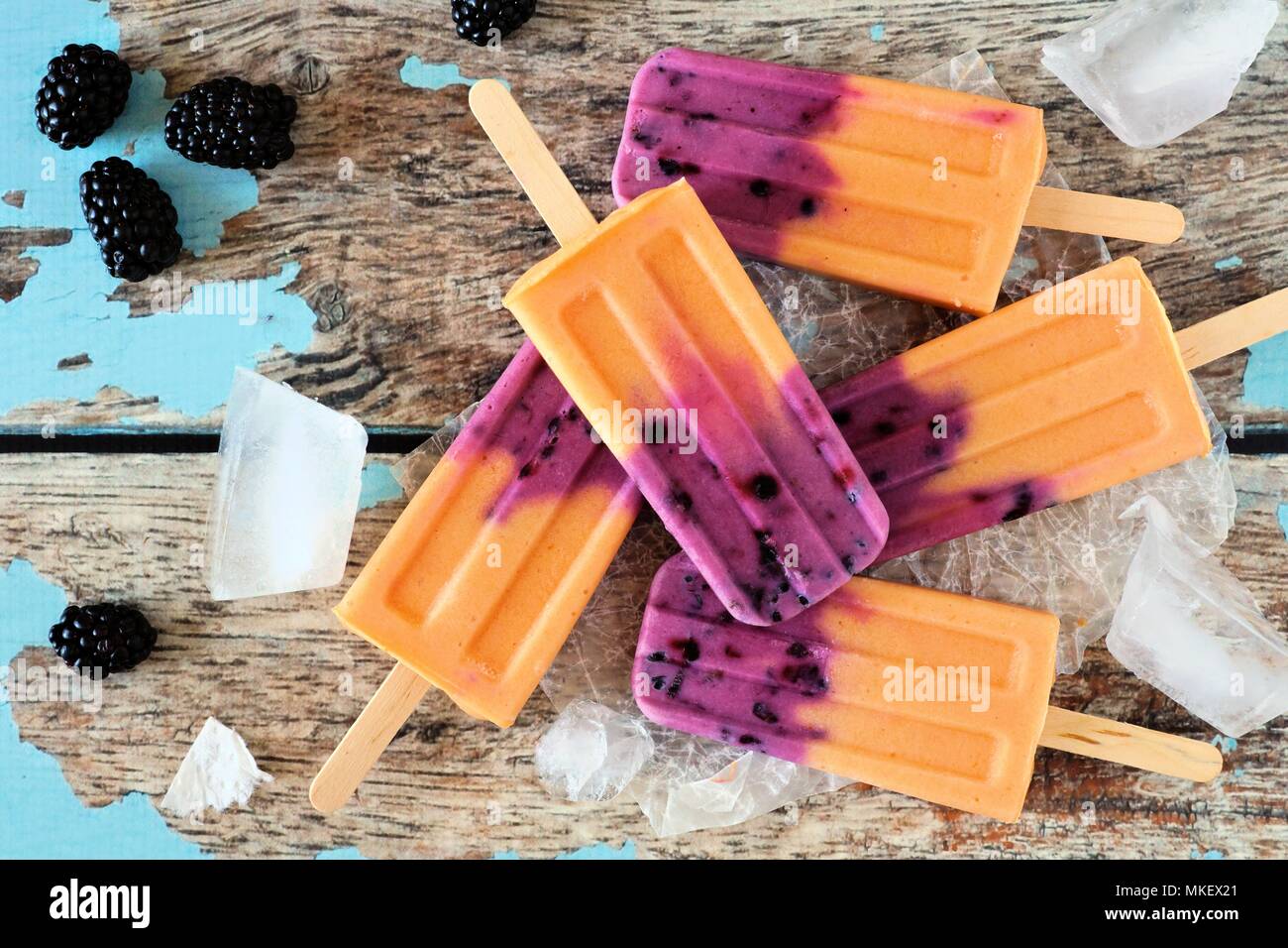 Mango blackberry ice pops in a cluster. Top view scene over a rustic wood background. Stock Photo