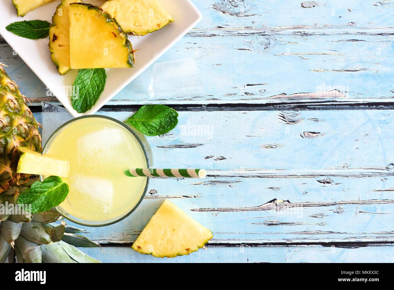 Glass of pineapple juice with fruit. Top view, side border on a blue ...