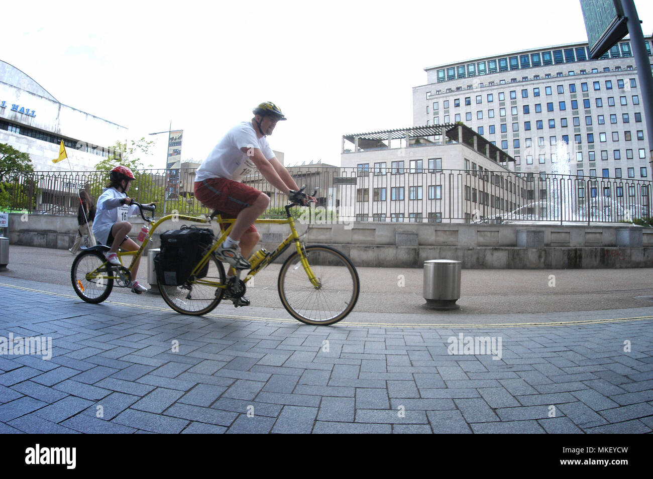 man on his bike towing a child in a bike trailer london city Stock