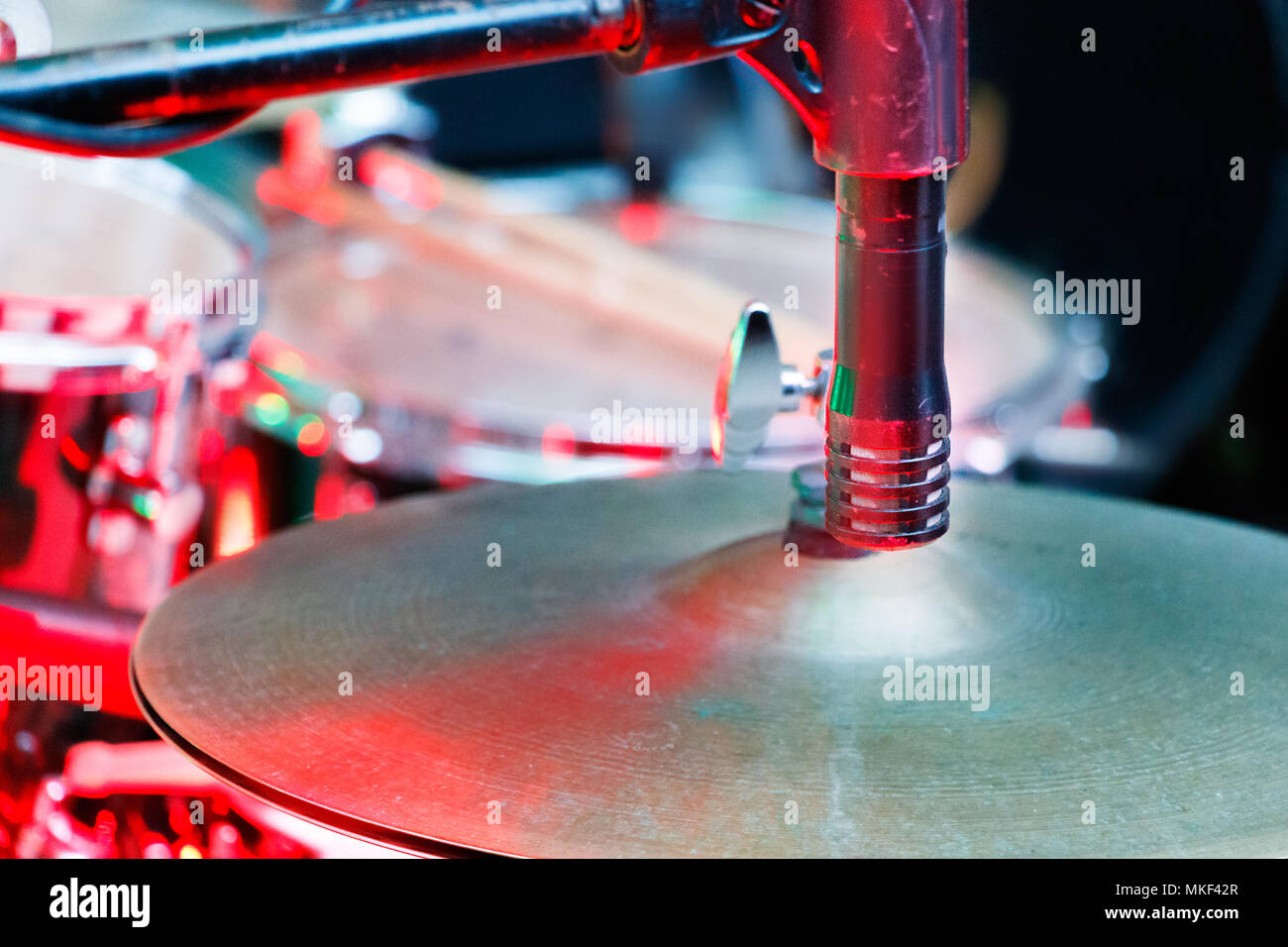 Closeup of a microphone placed close to a metal cymbal of a drums kit. Stock Photo