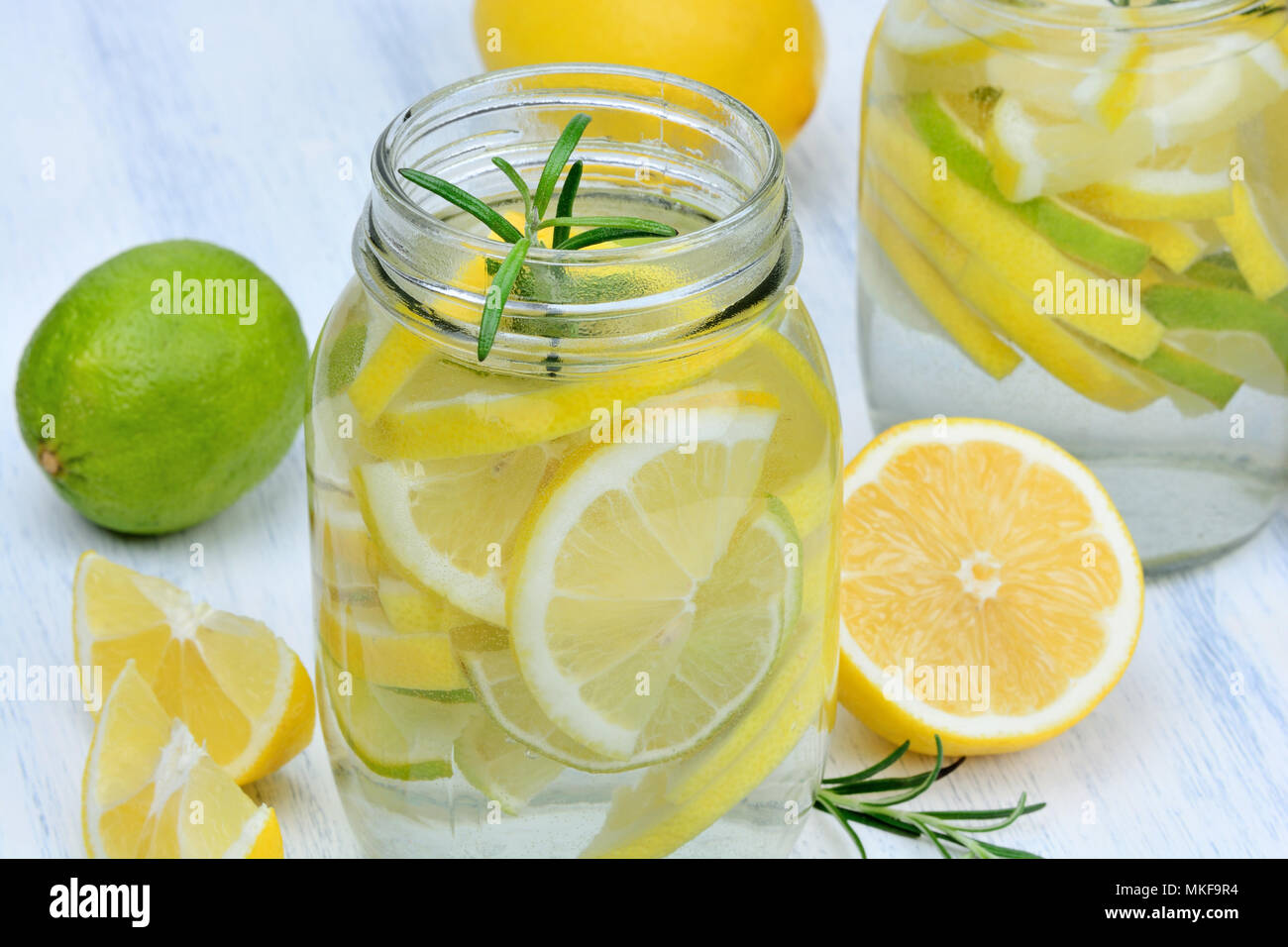 Detox water with lemon and rosemary in a jars on wood table Stock Photo