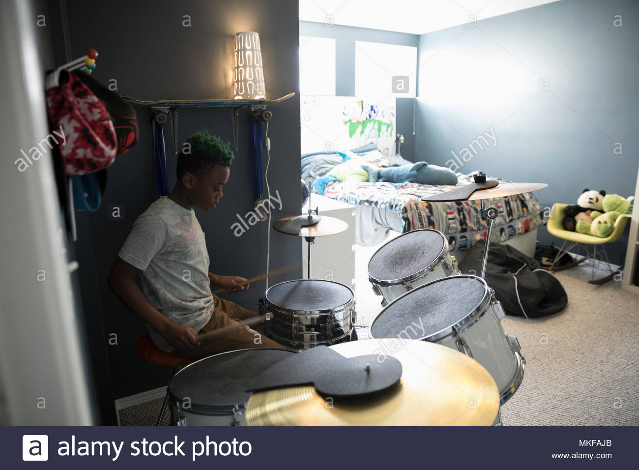 Boy playing drums in bedroom Stock Photo