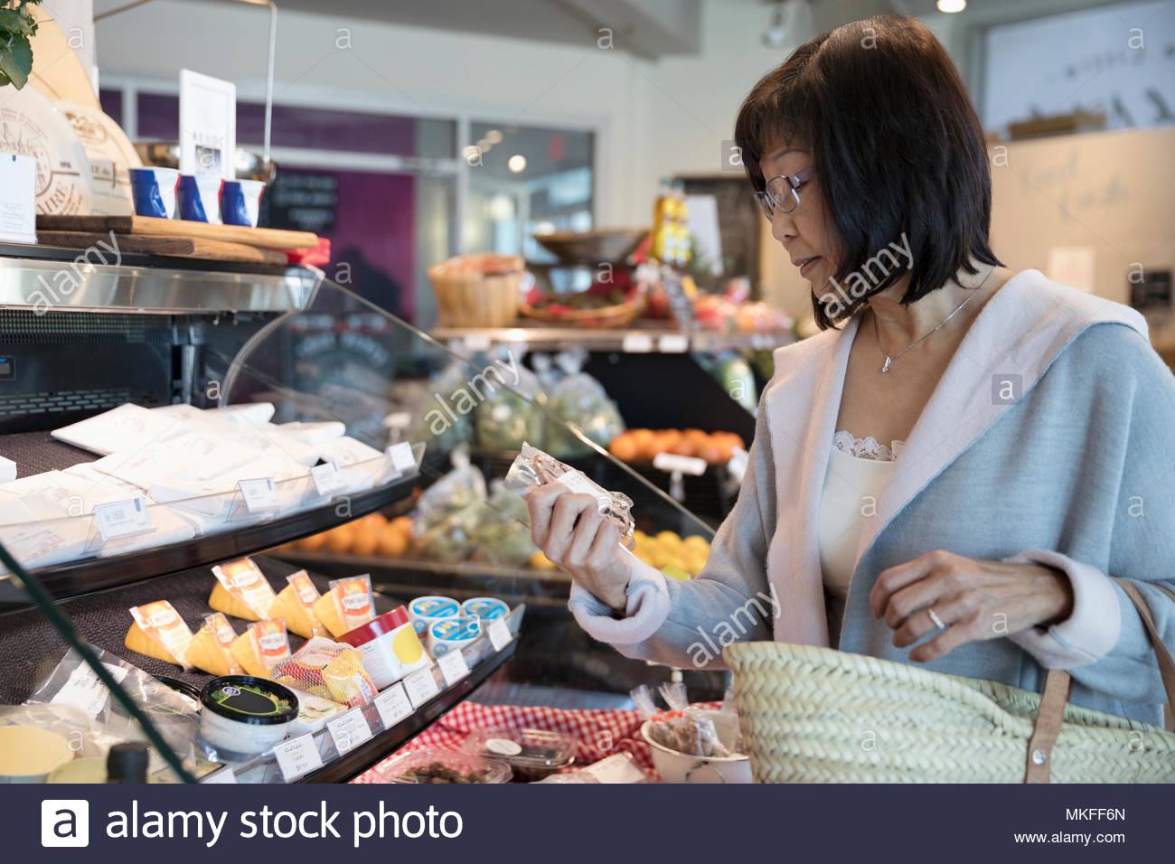 Senior woman browsing deli display in grocery store Stock Photo