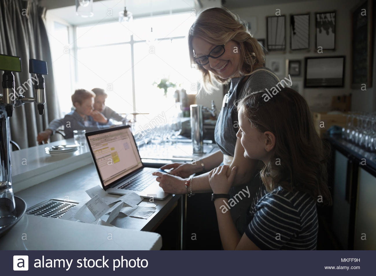 Family business owner mother and daughter working at laptop in cafe Stock Photo