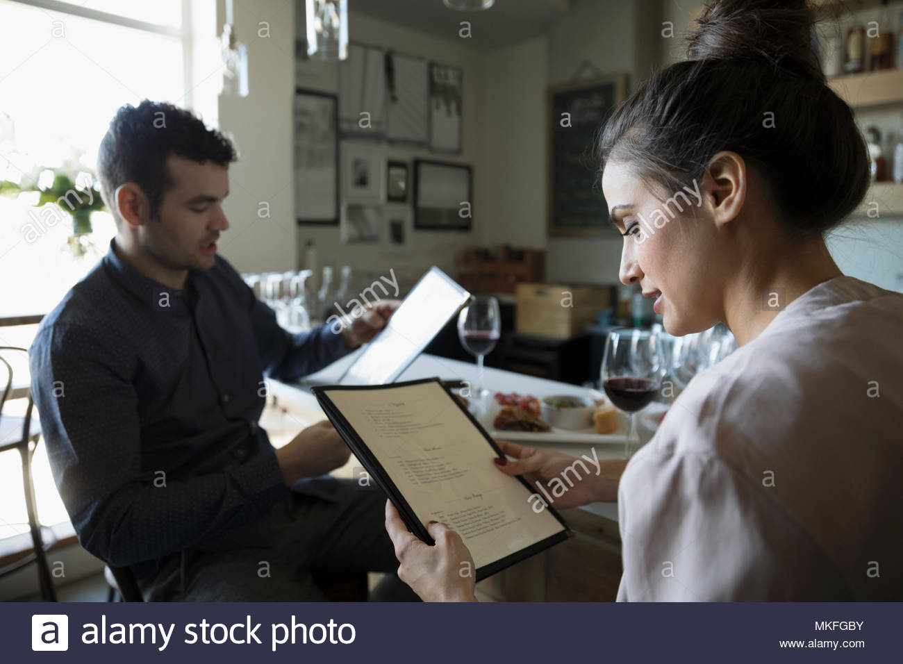 Young couple on date reading menu at bar Stock Photo