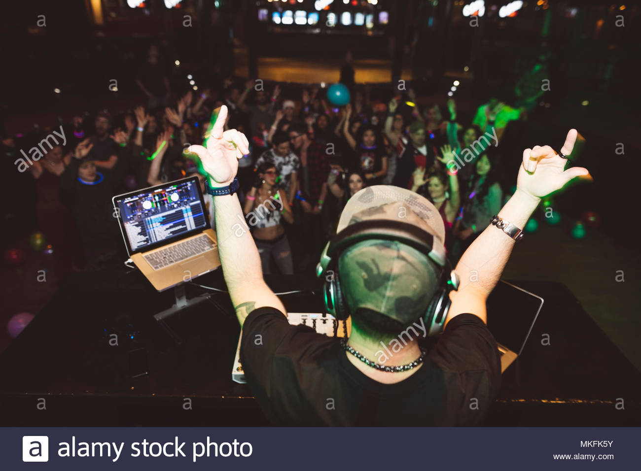 Enthusiastic DJ on stage gesturing to crowd in nightclub Stock Photo