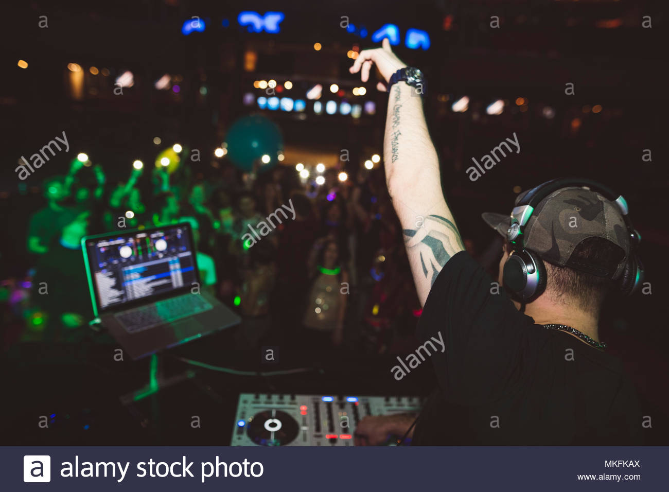 Enthusiastic DJ on stage gesturing to crowd in nightclub Stock Photo