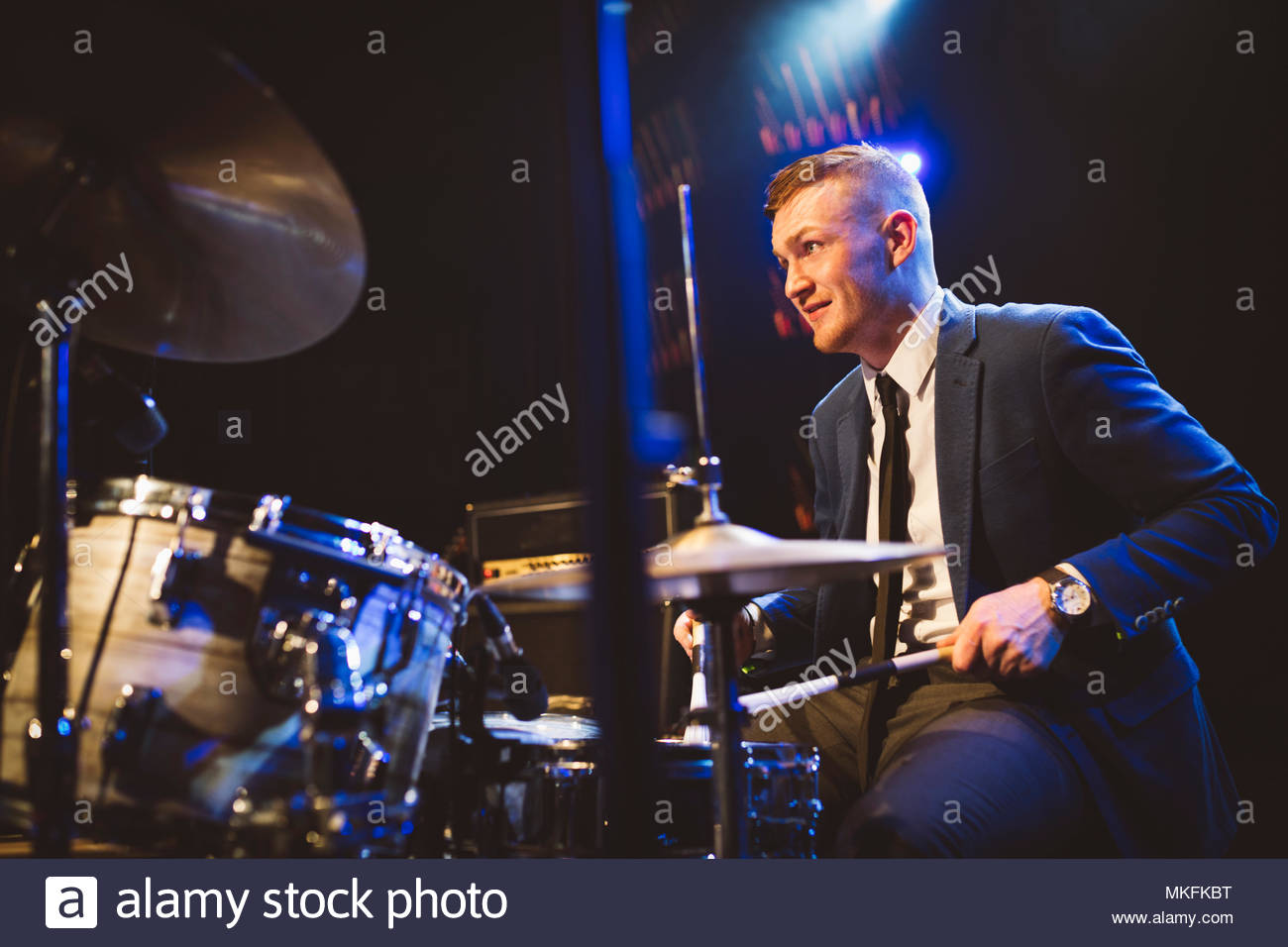 Confident musician playing drums on stage at music concert Stock Photo