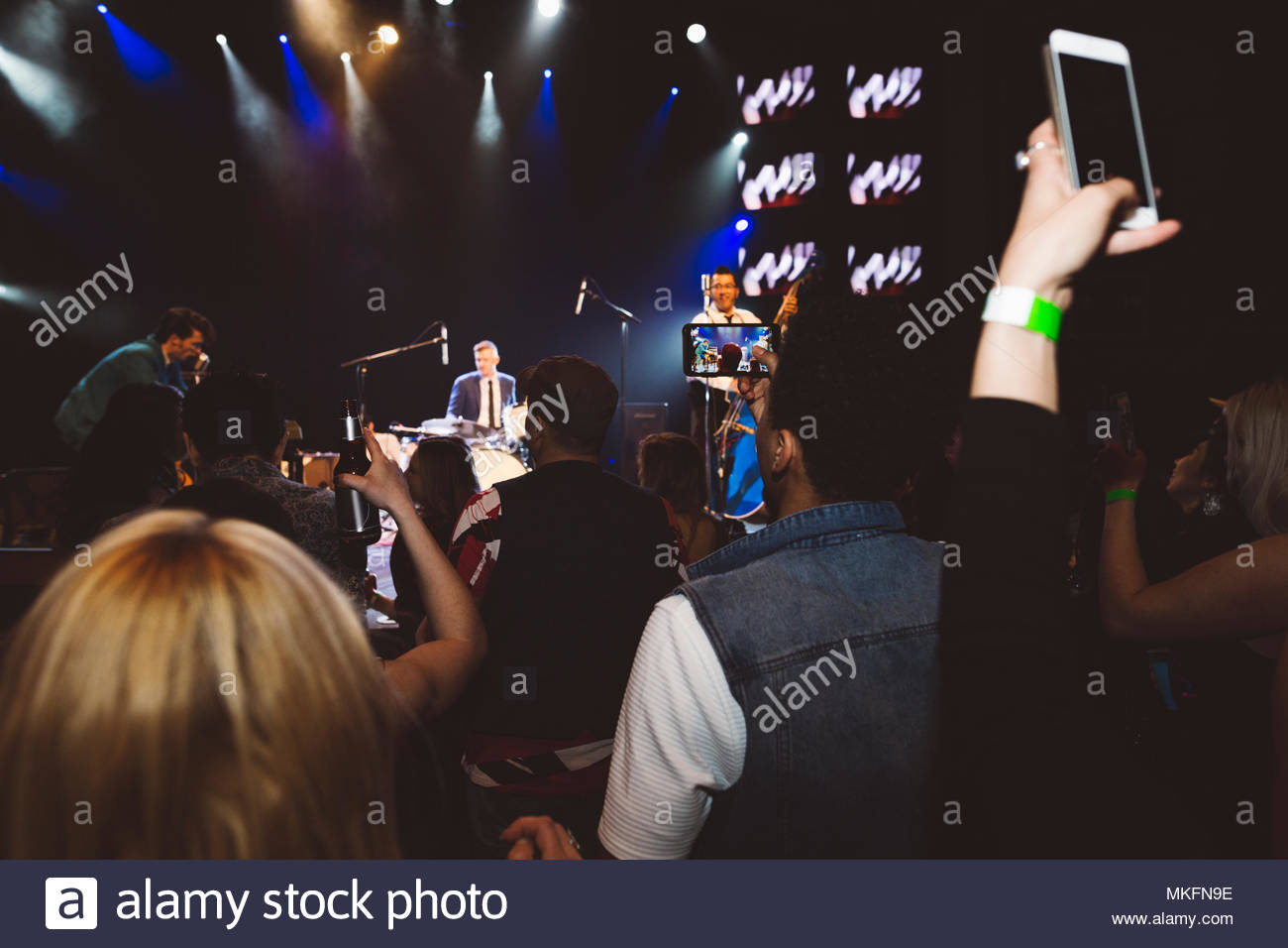 Crowd with smart phones videoing musicians performing on nightclub stage Stock Photo