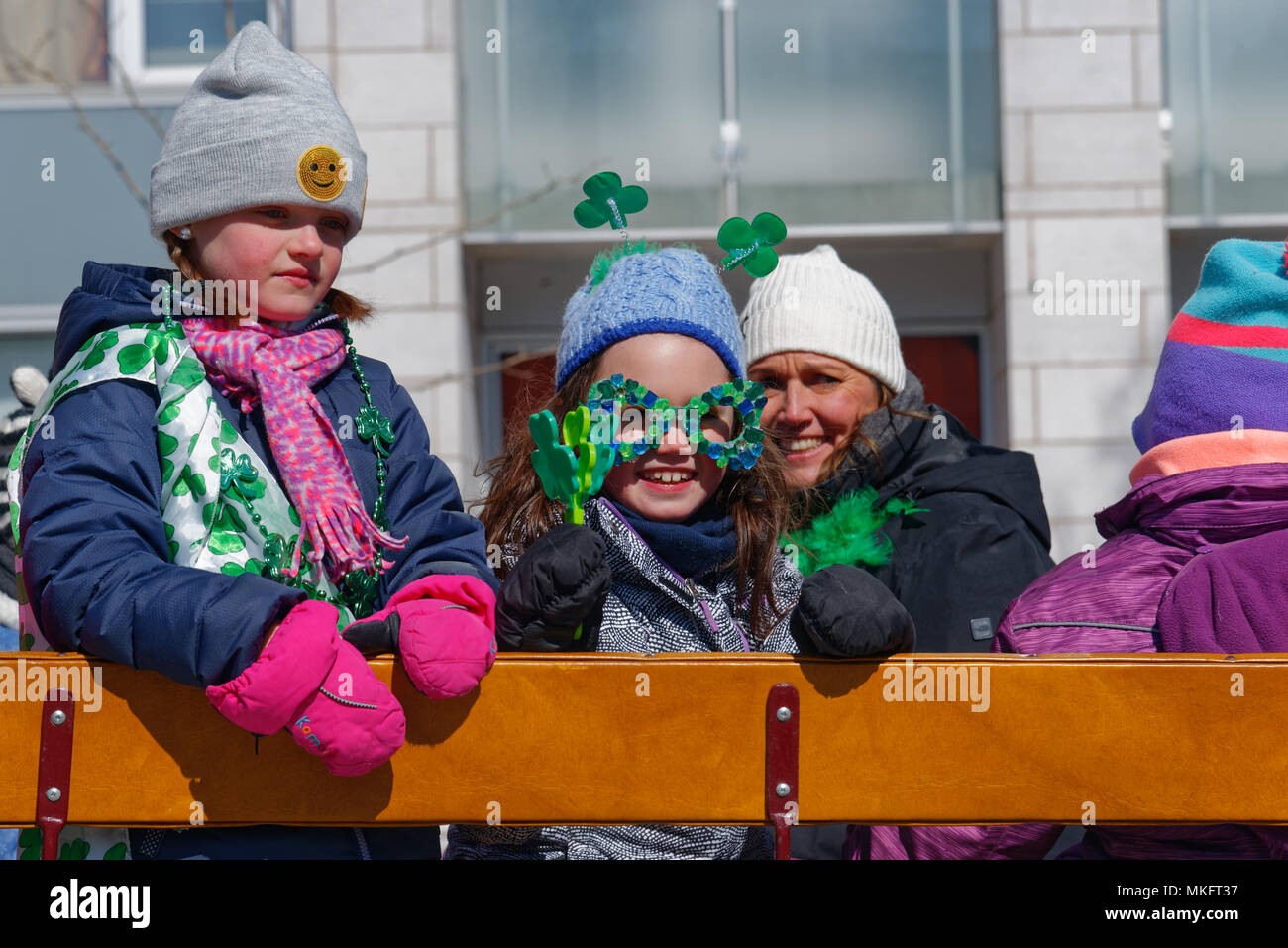 Children on a St Patrick's Day parade float smiling and waving to the crowd Stock Photo
