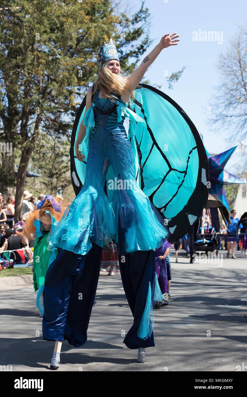 A woman in a fancy blue costume and crown walking on stilts at the May