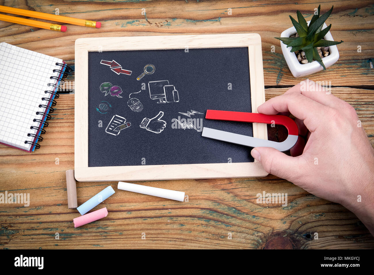 View of magnet attracting digital marketing, social network, employees, fans, clients, blackboard and chalk on wooden table Stock Photo