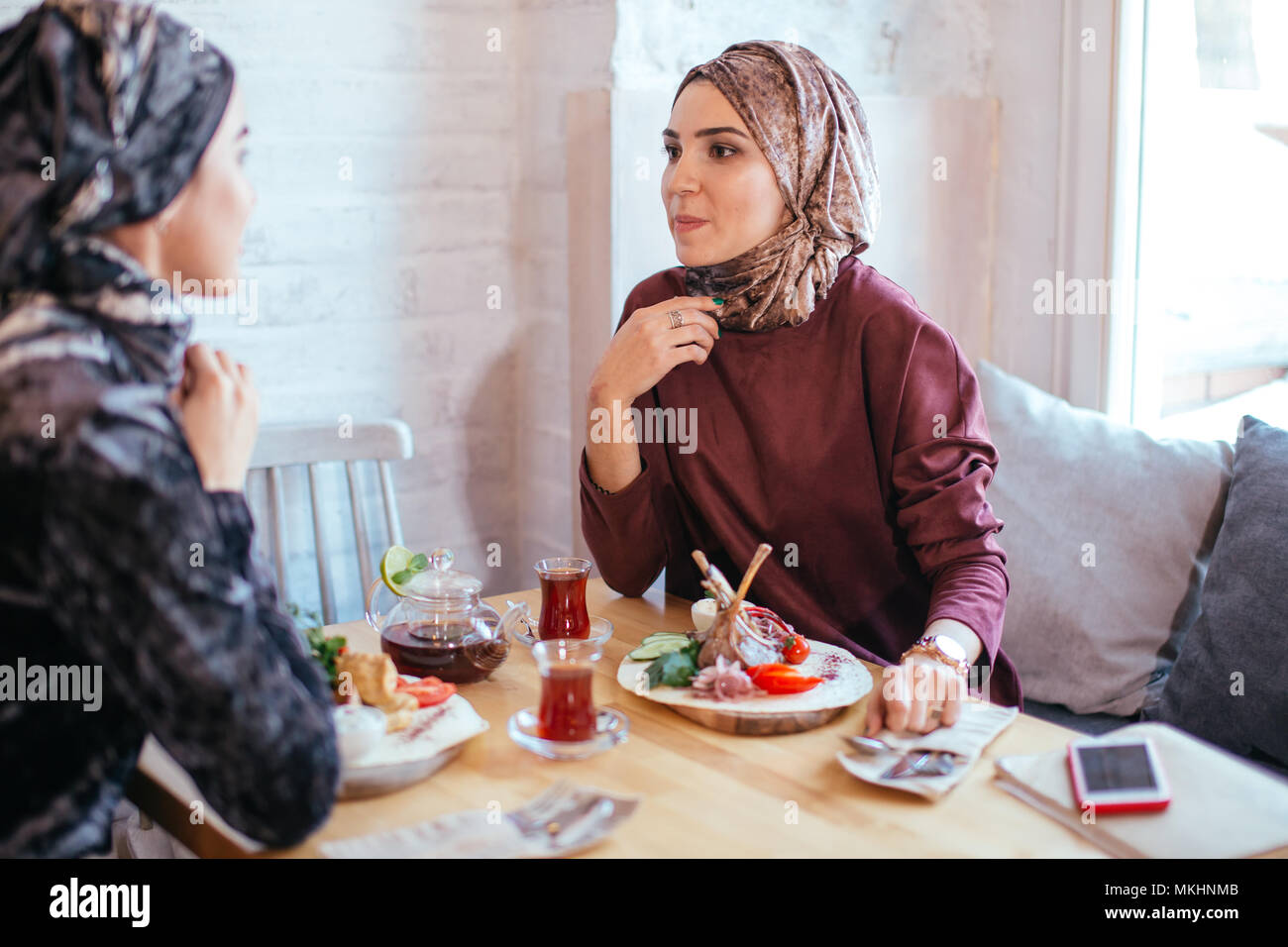 portrait of two woman talking while sitting on chair enjoying food